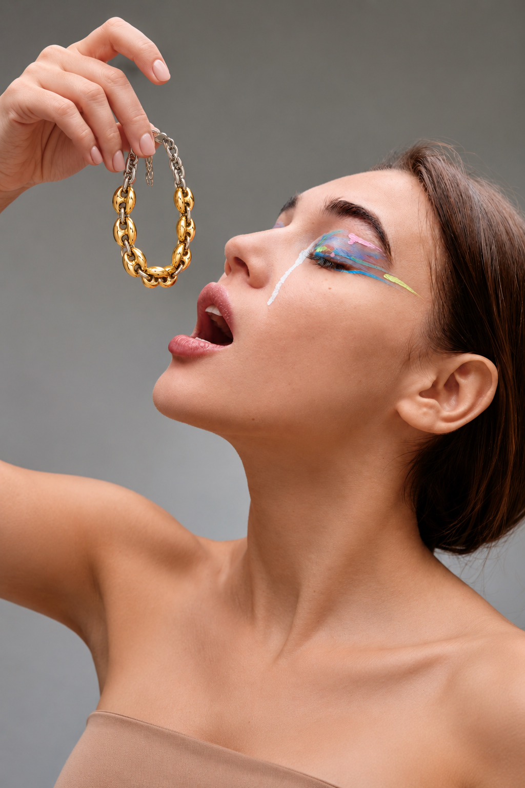 Model holding a two-tone chain bracelet beside her face