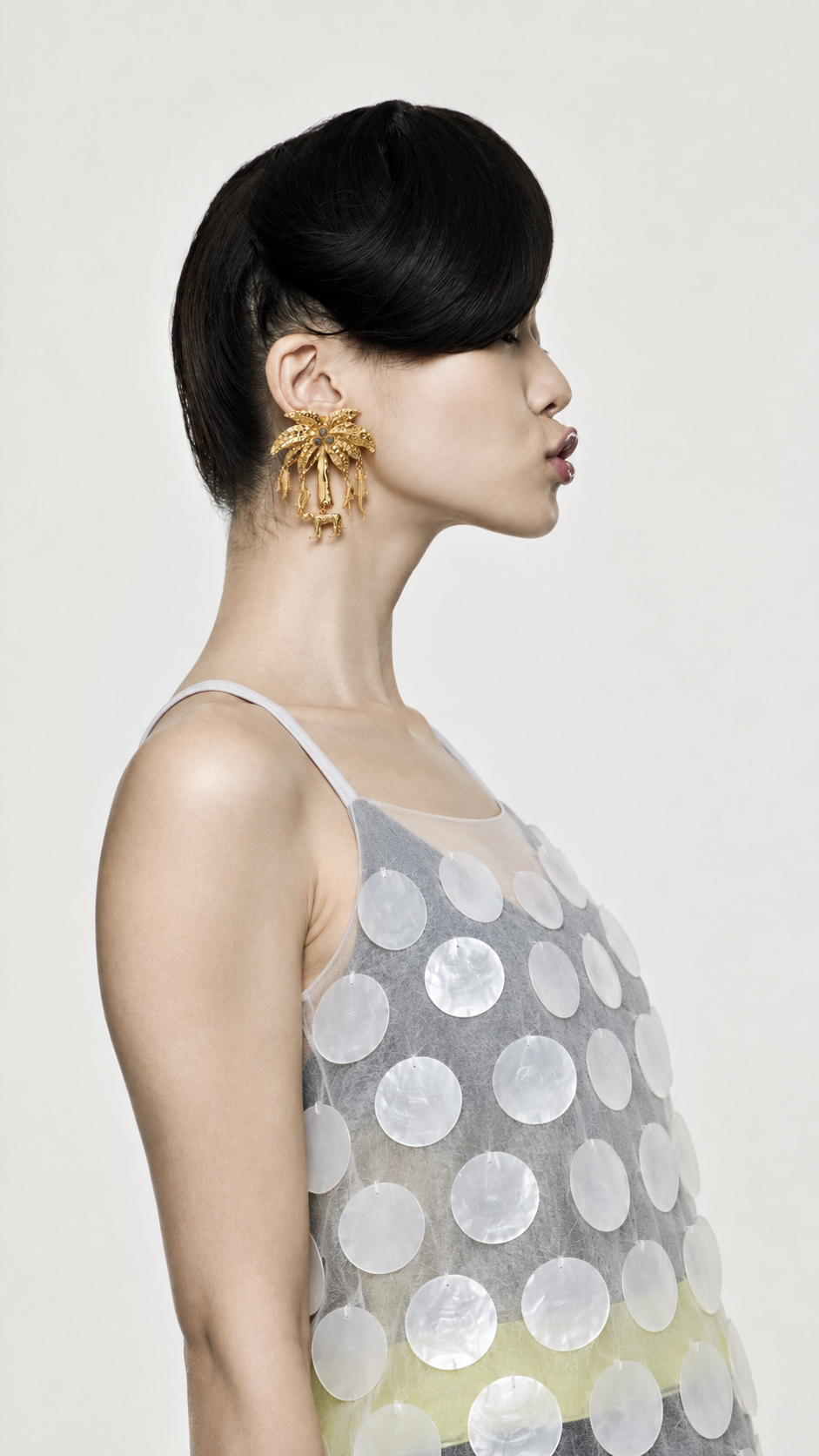 Profile portrait of a model wearing sculptural gold earrings